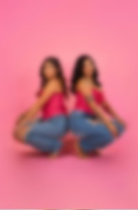 two women posing in front of a pink background
