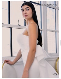 a woman in a white dress is posing in front of a window