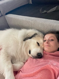 a woman laying on a couch with a white dog
