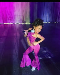 a young girl in a purple outfit posing for the camera
