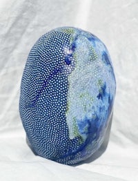 a blue and white ceramic ball on a white surface