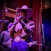 a man in a cowboy hat singing into a microphone