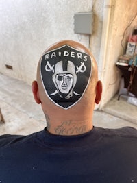 a man's head with an oakland raiders logo painted on it