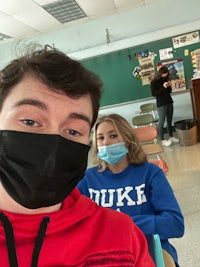 two people wearing face masks in a classroom