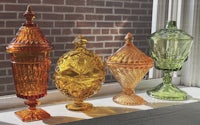 a row of colorful glass vases on a window sill