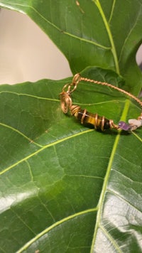 a wired bracelet sitting on top of a leaf