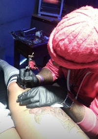 a man is getting a tattoo on his leg