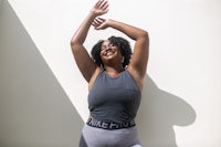 a black woman in a grey tank top and leggings is posing for a photo