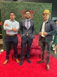 three men posing in front of a red carpet