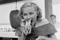 a woman is eating a hot dog in a restaurant