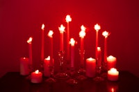 a group of red candles on a table in front of a red wall