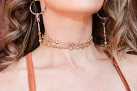a woman wearing a gold choker and hoop earrings