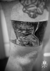 a black and white photo of a man with a tattoo on his thigh