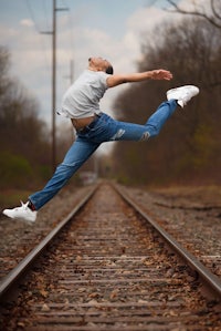 a dancer jumping on railroad tracks