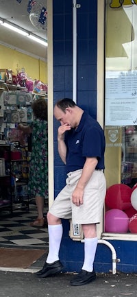 a man leaning against the side of a store