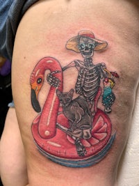 a tattoo of a skeleton sitting on a flamingo