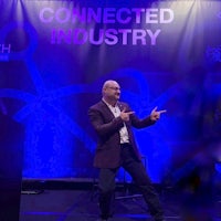 a man standing in front of a stage with the words connected industry