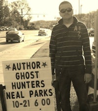 a man standing next to a sign that says author ghost hunters neal parks