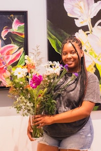 a woman holding a bouquet of flowers in front of paintings