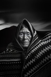 a black and white photo of an old woman in a blanket