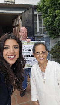 a woman and a man standing in front of a house with a sign