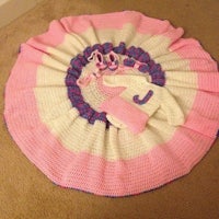 a pink and white crocheted blanket on the floor