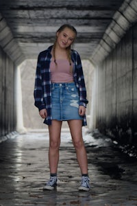 a girl in a denim skirt standing in a tunnel