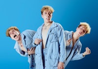 three men in blue clothes are posing in front of a blue background