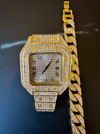 a gold watch with diamonds next to a chain