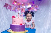 a little girl standing in front of a birthday cake