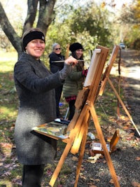 a woman holding an easel in a park