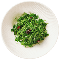 a white plate with arugula and cranberries