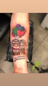 a tattoo of a couple with balloons on their forearm