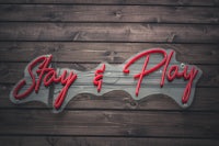 a sign that says stay and play on a wooden wall