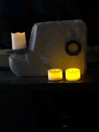three candles are sitting on a stone in front of a tv