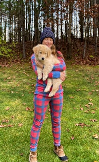 a woman holding a puppy in a plaid pajama