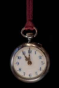 a silver pocket watch hanging on a red cord