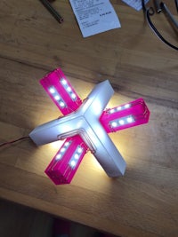 a pink and white led cross on a wooden table