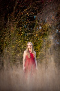 a woman in a red dress standing in tall grass
