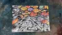 a watercolor painting of autumn leaves on a piece of cloth
