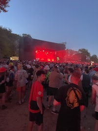 a crowd of people standing in front of a stage at dusk