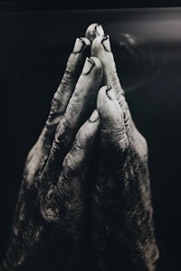 a black and white photo of a person's hands praying