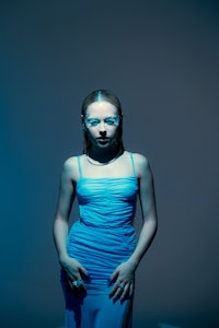 a woman in a blue dress posing in front of a blue background