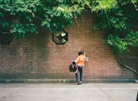 a woman walking down a brick wall with a bag