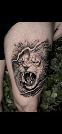 a tattoo of a lion on a man's thigh