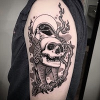 a black and white tattoo of a skull and a hawk