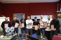 a group of people holding certificates in front of a computer