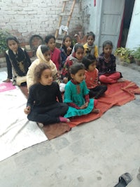 a group of children sitting on a blanket in front of a house