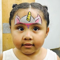 a little girl with a unicorn face painted on her face