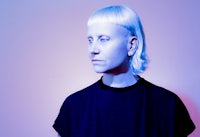 a woman with blue hair standing in front of a blue background